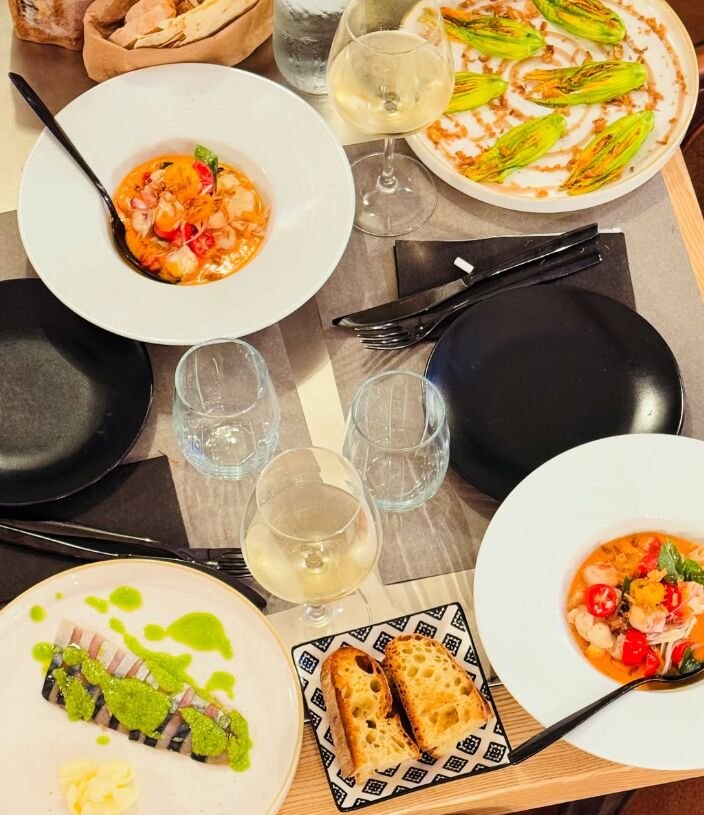 Piatti di pesce serviti in tavola con calici di vino bianco al ristorante di mare a Cabras